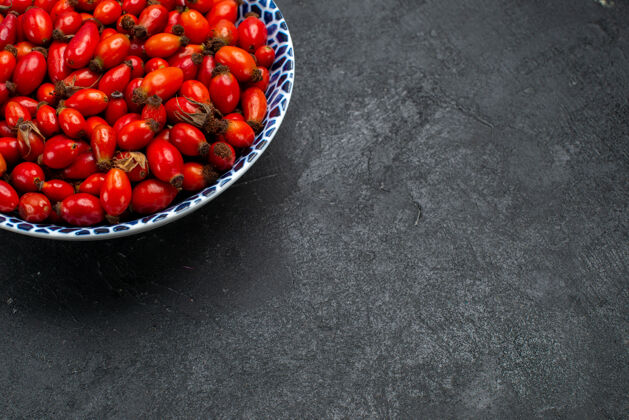 生的正面图红色水果成熟和酸味浆果盘内放在灰色桌上水果浆果色维生素树植物里面盘子桌子