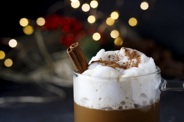 特写一个美味的圣诞咖啡肉桂和泡沫 在波基灯前卡布奇诺泡沫杯子