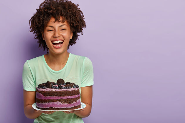 蛋糕生日快乐的女孩欢笑 捧着美味的大水果蛋糕 喜欢吃甜食 以提高血糖改善心情卷曲甜点搞笑
