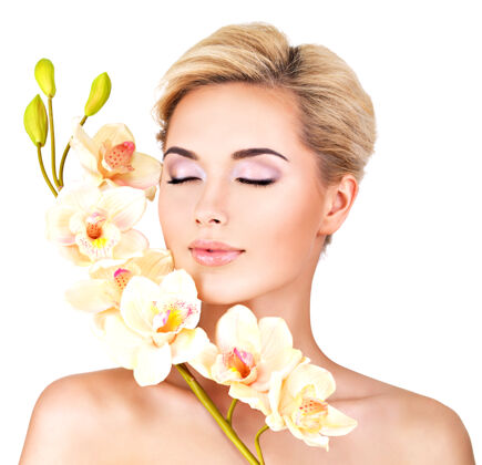 花年轻漂亮的女人美丽的脸 健康的皮肤和粉红色的花朵在身体上-隔离在白色触摸护理美容