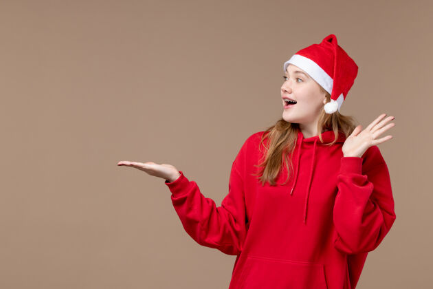 人正面是棕色空间上穿着红色斗篷的圣诞女孩节日帽子漂亮