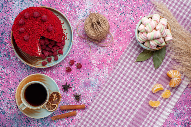 胭脂红色覆盆子蛋糕的顶视图 粉色表面有肉桂和茶马克杯饼干桌子
