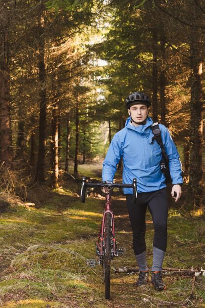 自行车骑自行车的人穿着蓝色外套 戴着头盔在高大的公园里森林道路户外