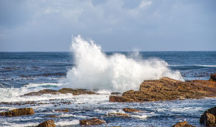 岩石在阳光的照耀下 岩石被波涛汹涌的大海包围 在南非的白天 天空多云旅游海洋岩石