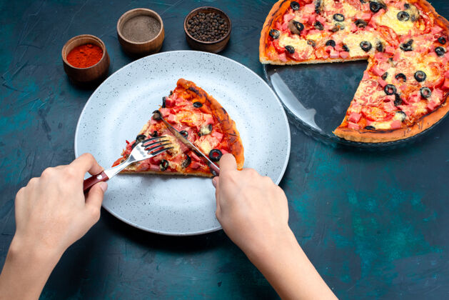 橄榄半顶视图烤美味披萨橄榄香肠和奶酪女性吃它在蓝色的桌子上香肠蓝色糕点