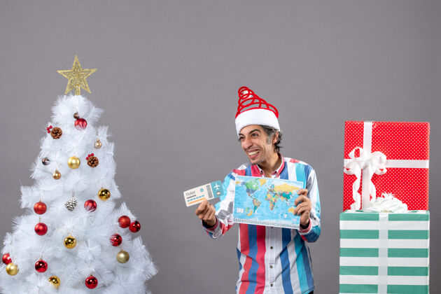 圣诞树正面图笑人拿着世界地图和门票票礼品盒笑的人