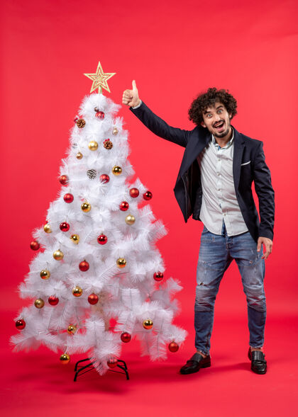 人圣诞庆祝快乐有趣的年轻人站在圣诞树旁做ok手势好快乐手势