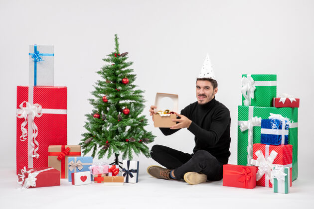礼物正面图：年轻人围坐在白色的墙上 手里拿着礼物和玩具人快乐雪