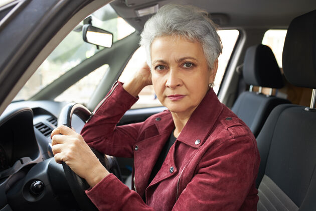 女性一幅严肃的退休妇女的画像 留着短发 坐在车里 通过驾驶考试 感到紧张自信女商人道路