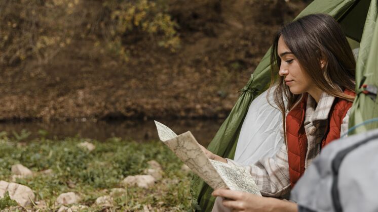 旅游快乐的野营女孩在森林里查看地图侧视图自然旅行旅行者