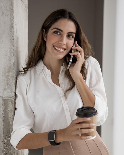优雅微笑女商人一边喝咖啡一边打电话的前视图经理个人智能手机