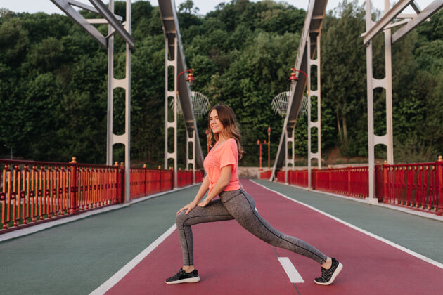 锻炼梦幻卷曲的女人穿着运动裤伸展在煤渣路浪漫女孩训练的户外肖像健康运动女士