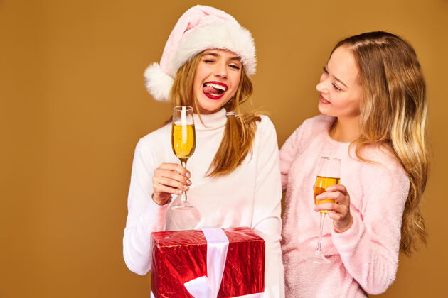 新的带着大礼盒的模特戴着酒杯喝香槟庆祝新年最好的年轻朋友