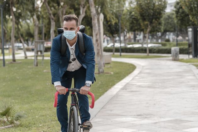 人戴着医用面罩骑自行车的男人运动的骑自行车骑自行车的