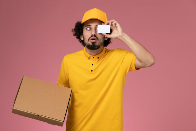 名片正面图：身着黄色制服的男快递员拿着食品递送箱和卡片放在光墙上成人制服肖像