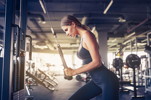 强壮健身女人锻炼三头肌举重在健身房运动性感的女人在健身房用机器做运动身体勇气视频