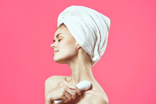 专业迷人的女人用毛巾在头上按摩脸部放松粉色超声波皮肤科美丽