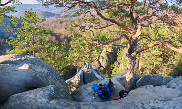 上升大石头上睡袋里的游客男女自由登山者山