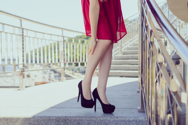 受伤太小的大鞋子美容黑红色短装医疗条件痉挛肌肉概念特写低视角照片美丽优雅的女士抱着腿按摩的地方肖像城市脚踝刹车