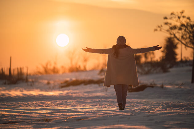 寒冷一个穿着暖和衣服的女人独自站在雪白的草地上 欣赏冬日乡间如画的日落孤独全长和谐