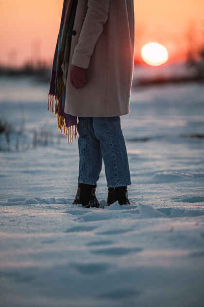 环境日落时分 在冬天的乡下 在新鲜的白雪上 收割着一个穿着暖和的衣服和靴子 面目全非的女人雪活跃路径