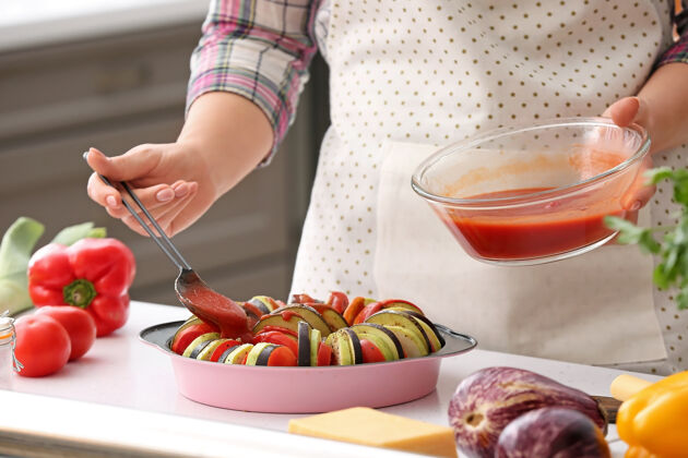 人女人在厨房里用番茄酱拌新鲜蔬菜欧芹自制托盘