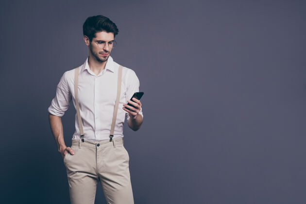男性成功商人手持电话的肖像打字公司电子邮件穿着正装衬衫吊带裤规格时尚男士写作