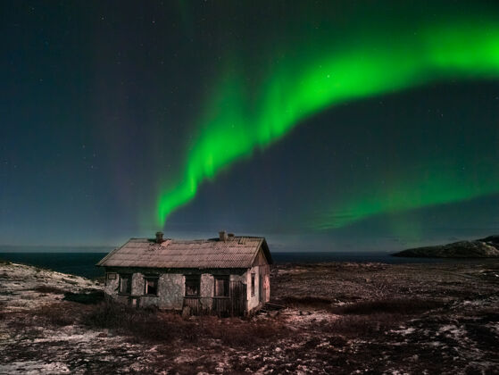 旅行北方星空下一座废弃的老房子夜间极光极光景观山长时间曝光极地
