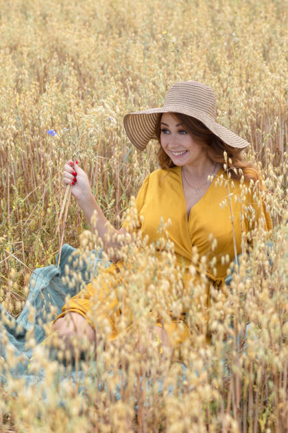 天空在一个阳光明媚的夏日 一位年轻漂亮的孕妇穿着黄色的裙子 戴着黄色的帽子 走过一片麦田农业收获生命