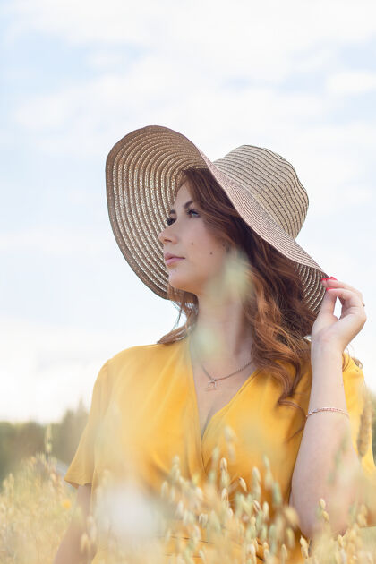 农场在一个阳光明媚的夏日 一位年轻漂亮的孕妇穿着黄色的裙子 戴着黄色的帽子 走过一片麦田欢呼麦田自然