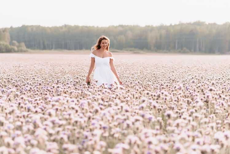春天美丽快乐的女人 穿着白色的连衣裙 在一片夏日的花丛中 在大自然中绽放浪漫白天
