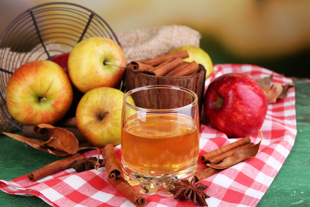健康苹果酒与肉桂棒 新鲜苹果和秋叶在木制背景玻璃组成热甜肉桂