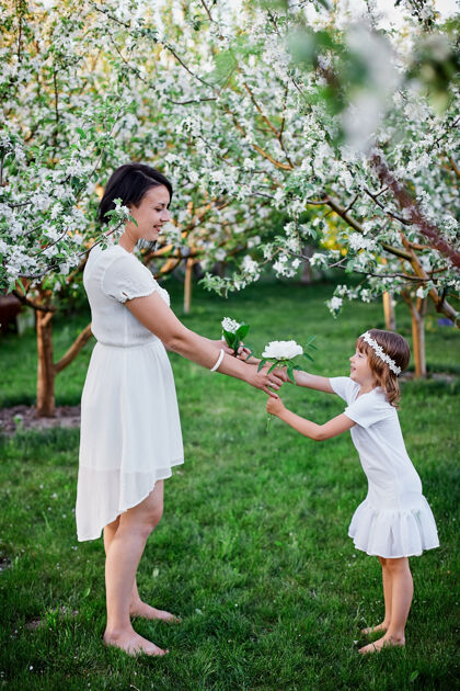 公园快乐的女人和孩子 可爱的女儿和母亲在春天的花园里 穿着白色的衣服在户外 春天来了母亲节假期概念欢笑乡村开花