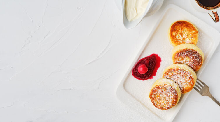 浆果芝士饼或油炸白芝士薄煎饼 撒上糖粉 盘中放上小红莓果酱和酸奶油咖啡自制甜点