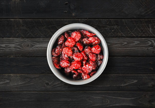 营养厨房桌子上碗里的小红莓黑色木质背景顶视图甜食水果自然