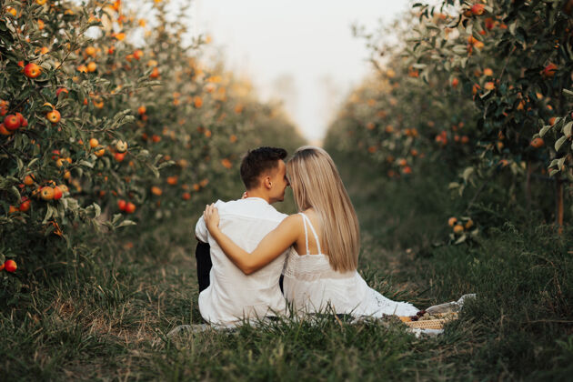 生态在苹果园的夏日野餐中 一对幸福的夫妇正在一起放松和喝酒举行一起爱