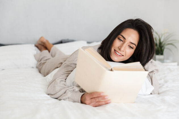 沙发美女30多岁看书的照片 而躺在床上的白色亚麻布在家里成人舒适吸引
