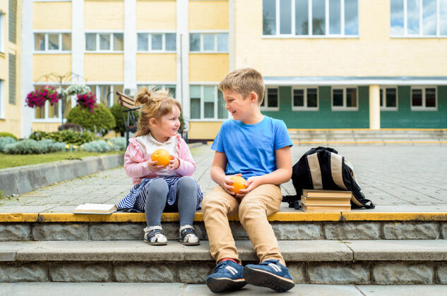 欢呼快乐的孩子们白天在校园里玩耍时间学校早餐 水果和果汁.stack教科书 书快乐友好的兄弟姐妹幼儿园散步可爱