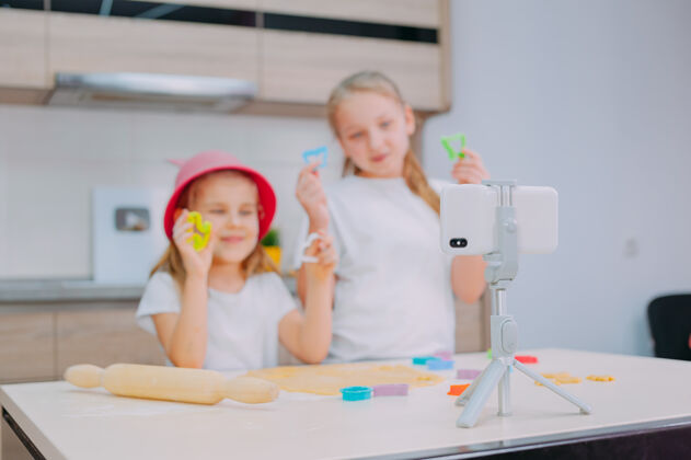 视频两位姐妹博客作者正在厨房准备饼干 并在智能手机上拍摄烹饪视频孩子女孩宝宝