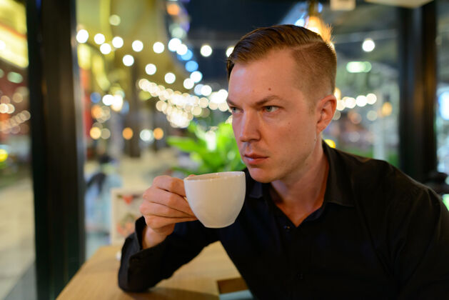 城市年轻英俊的斯堪的纳维亚商人在咖啡店放松的画像咖啡馆坐着斯堪的纳维亚人