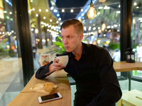 城市年轻英俊的斯堪的纳维亚商人在咖啡店放松的画像坐着现代咖啡