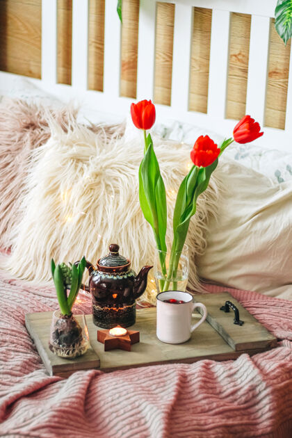 格子舒适的床上放着茶叶和春花的木制托盘 垂直照片高质量的照片早餐郁金香床