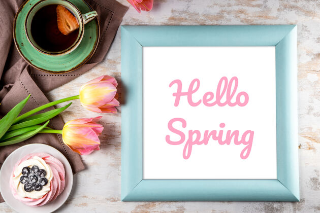 字母框架上有铭文“你好 春天” 粉色郁金香 蛋糕和一顶茶 背景为白色木质高质量的照片花开花题词