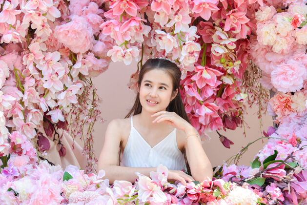 健康美丽的亚洲女人穿着白色的裙子坐在美丽的粉红色的花时尚漂亮微笑