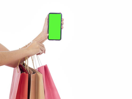 消费者拿着白屏智能手机和白墙上购物袋的女人们应用程序手银行