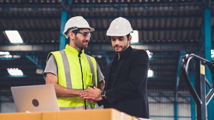 技术员两个工人在工厂里工作 讨论生产计划仓库计算机生产