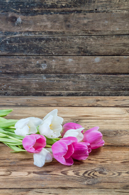 礼物粉色和黄色的郁金香花在质朴的木制背景上木板花瓣浪漫