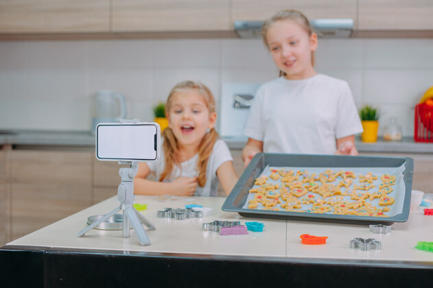 相机两位姐妹博客作者正在用智能手机制作饼干和拍摄培训视频美味妹妹糕点