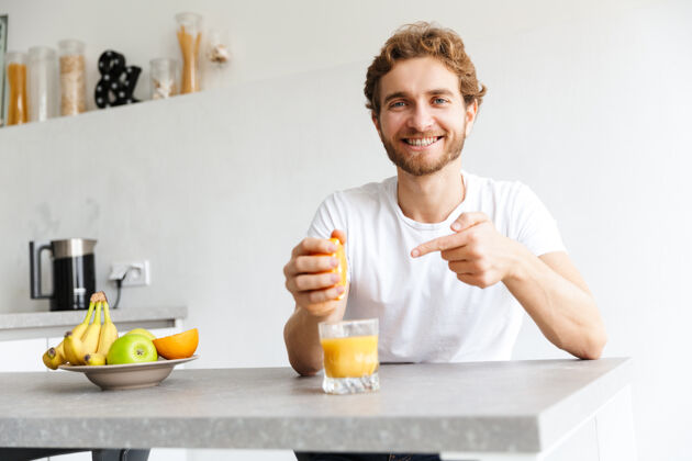成人图为一位快乐的留着胡子的年轻人在家里用水果做果汁白种人果汁文学