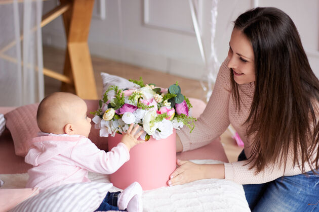 小快乐家人母亲带着她的小宝宝在明亮的室内生活房间妈妈用礼物和鲜花庆祝情人节有趣在一起父母